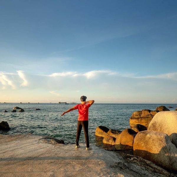 Silhouette of a person stretching against a sunrise, symbolizing energy.